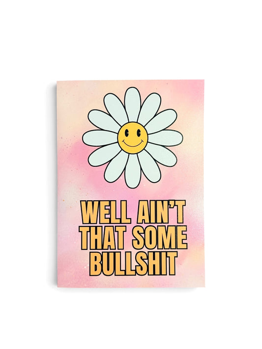 A rectangular card with a pink watercolor background, featuring a large smiling daisy flower and the text 'WELL AIN'T THAT SOME BULLSHIT' in bold yellow letters.