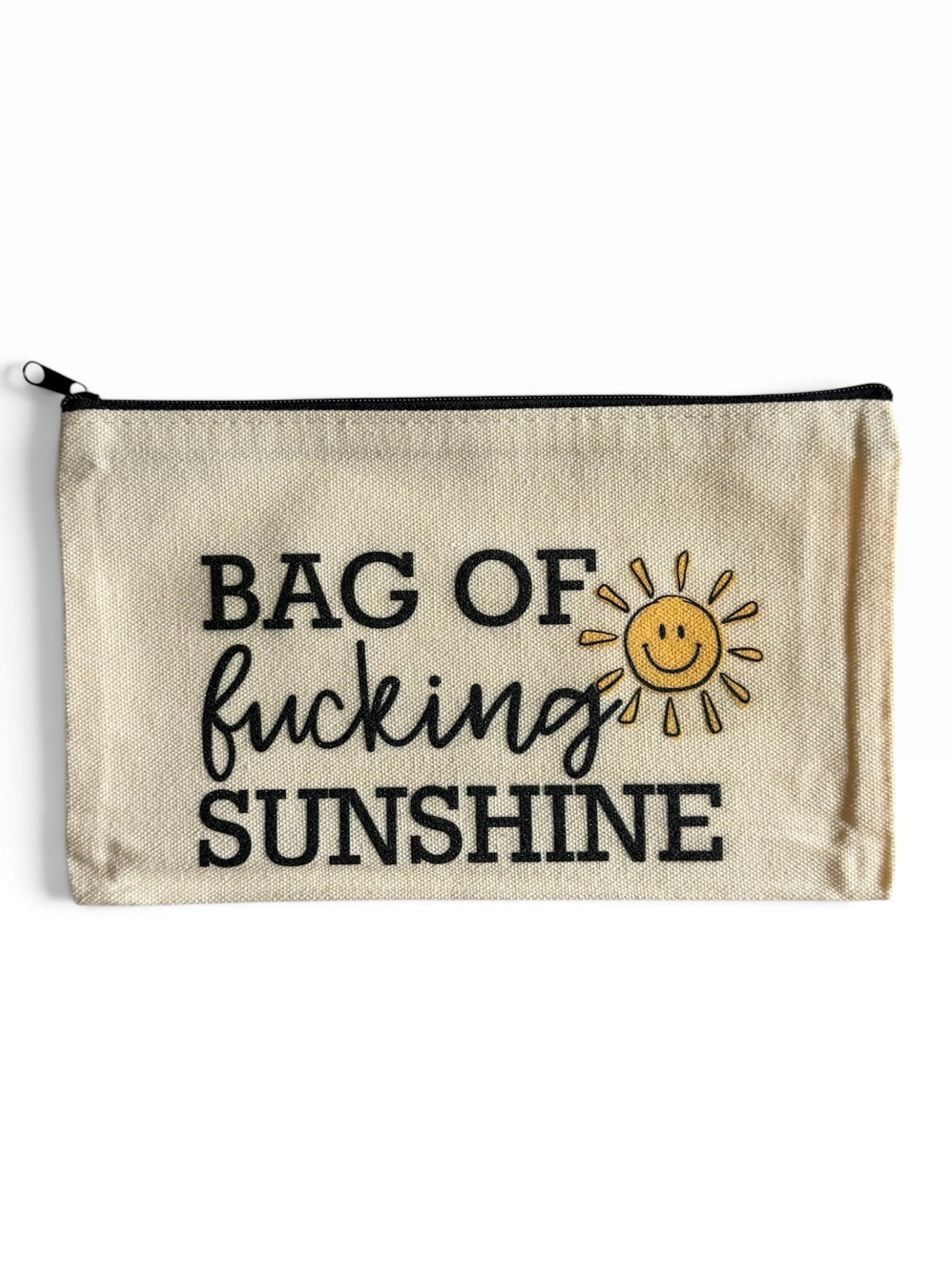 A beige canvas zippered pouch with black text reading 'BAG OF fucking SUNSHINE' and a small yellow smiling sun graphic, shown on a plain white background.