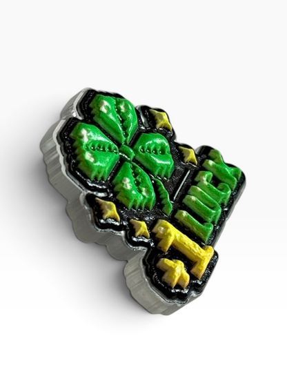 A side view of an acrylic uv printed pin with a four leaf clover and words '+1 luck' against a white background