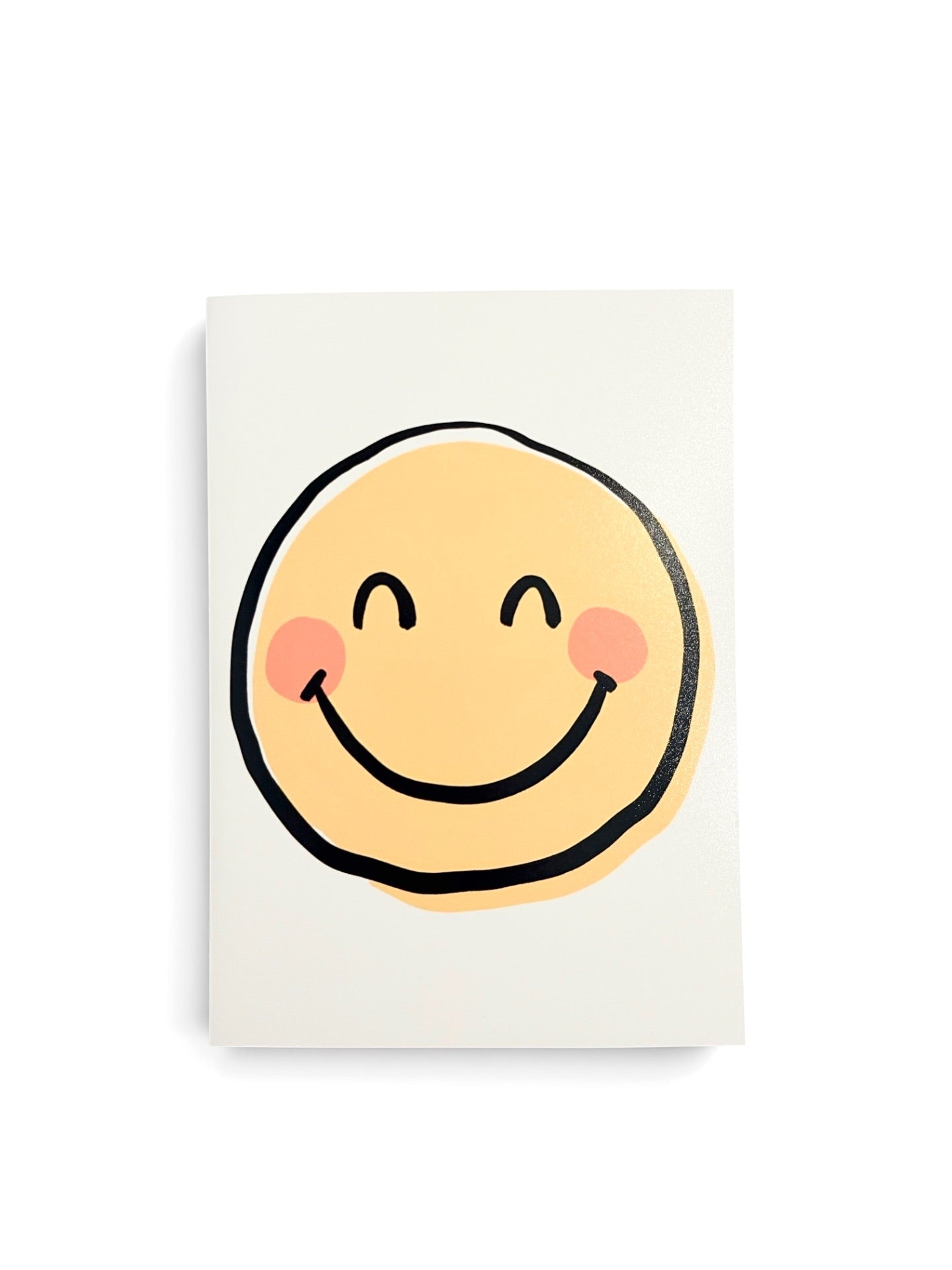 A minimalist art print featuring a simple yellow smiley face with black outlines and pink cheeks on a white rectangular card, set against a clean white background.