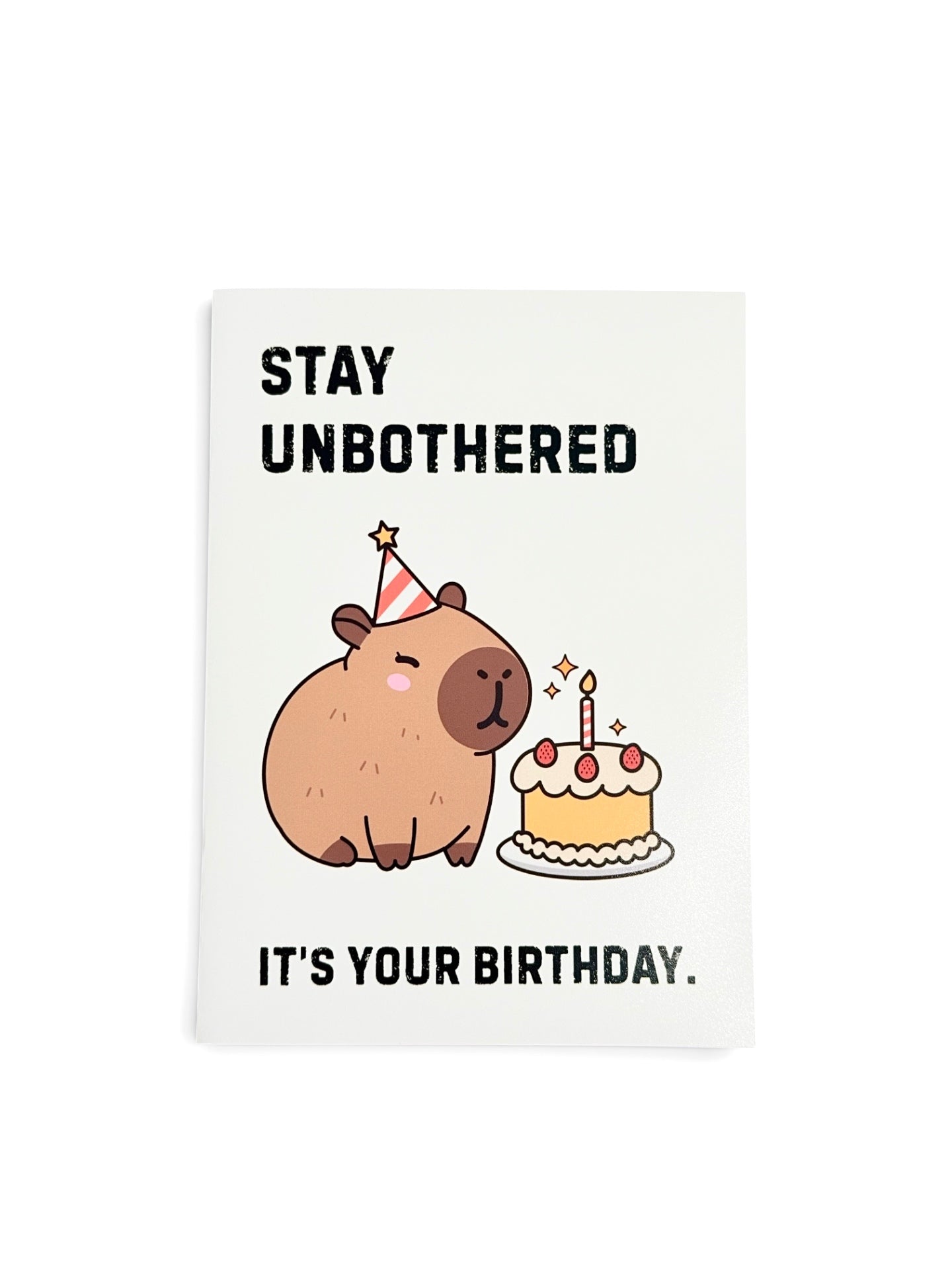 A rectangular card with a white background featuring a cute cartoon capybara wearing a party hat next to a birthday cake, with the text 'STAY UNBOTHERED' at the top and 'IT'S YOUR BIRTHDAY.' at the bottom.