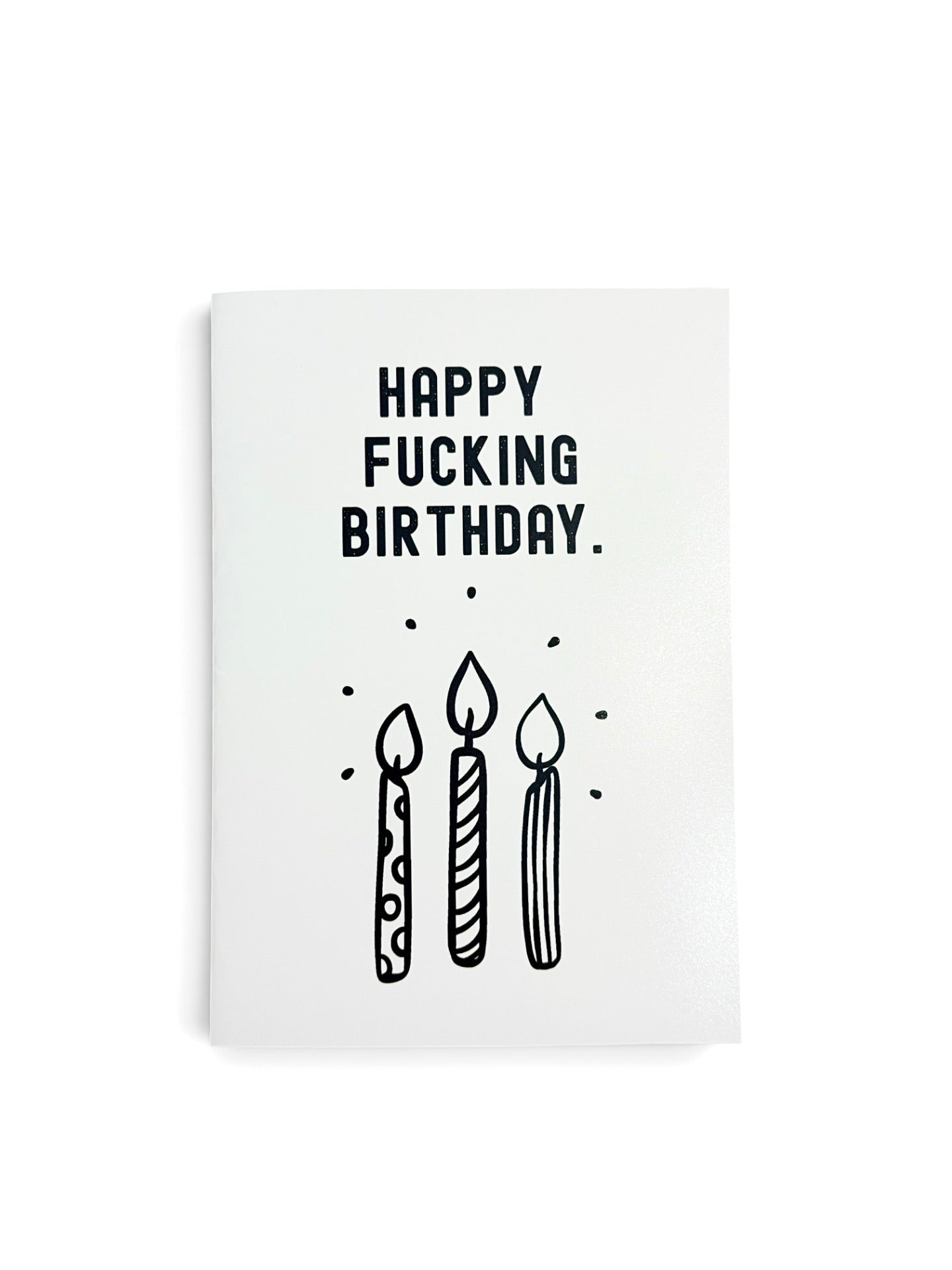 A white greeting card with black text reading 'HAPPY FUCKING BIRTHDAY.' and a simple black line drawing of three candles, shown on a white background.