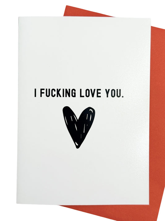 A white greeting card with the text 'I FUCKING LOVE YOU.' and a black heart graphic, shown with a red envelope behind it on a white background.