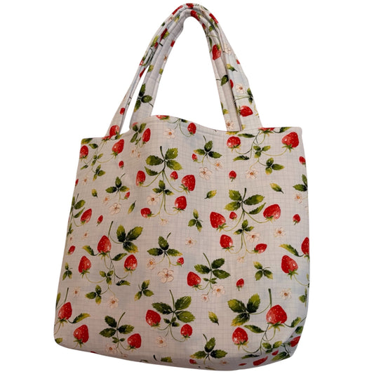 A fabric tote bag with a repeating strawberry and leaf pattern on a light beige background, featuring two shoulder straps.