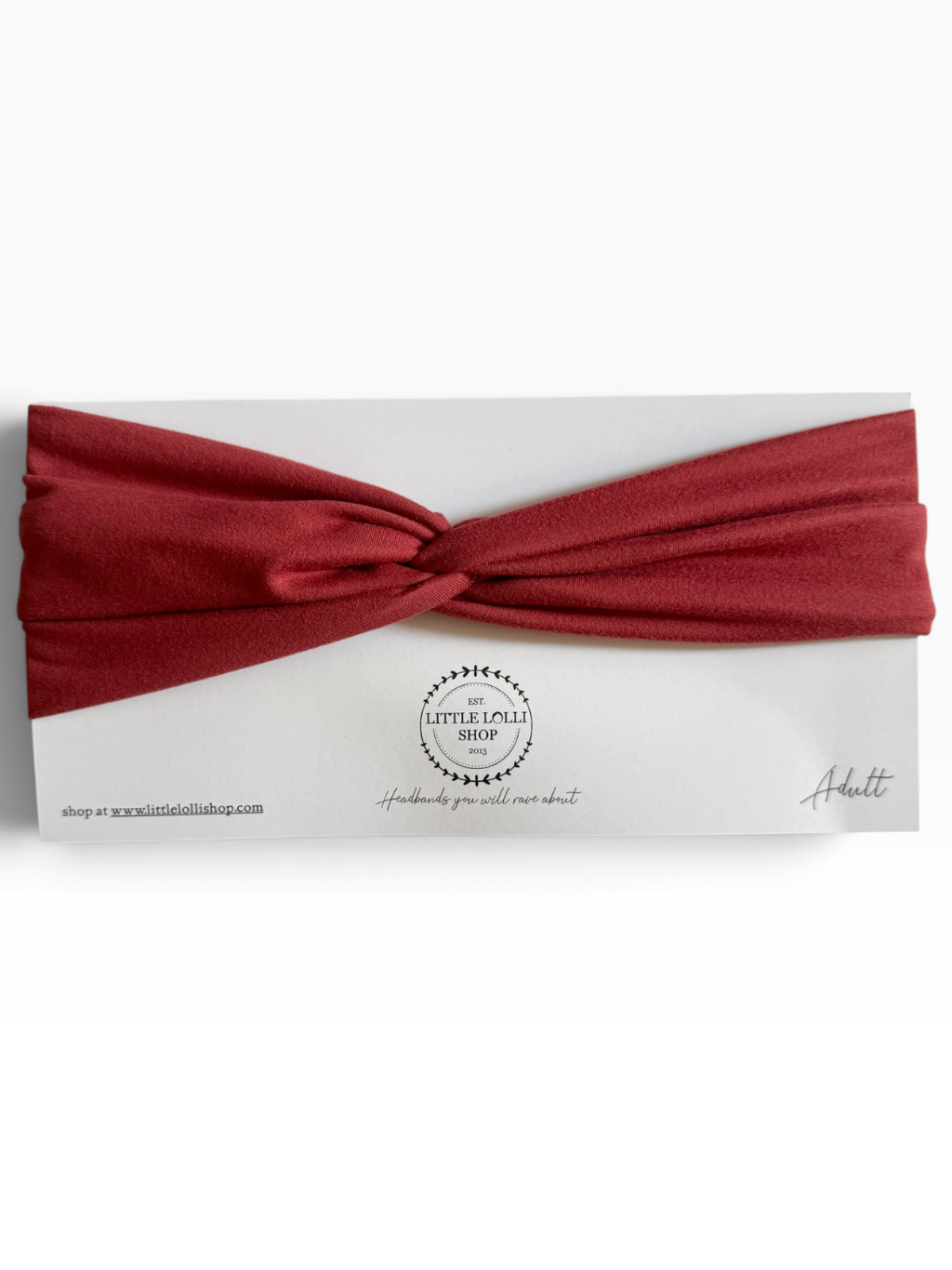 A knotted headband in a brick red color, presented on a white backing card with the brand name 'Little Lolli Shop' visible in the center.