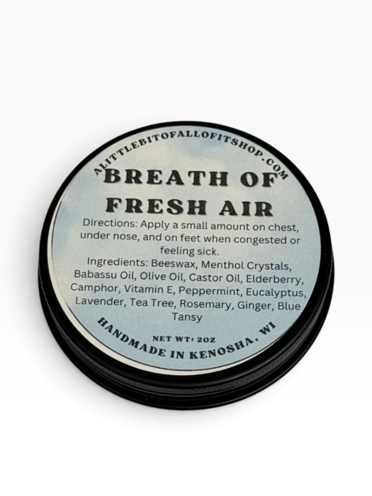 A round black tin of 'Breath of Fresh Air' home fragrance oil by A Little Bit of All of It Shop, featuring a light blue-gray label with black text detailing ingredients and directions.