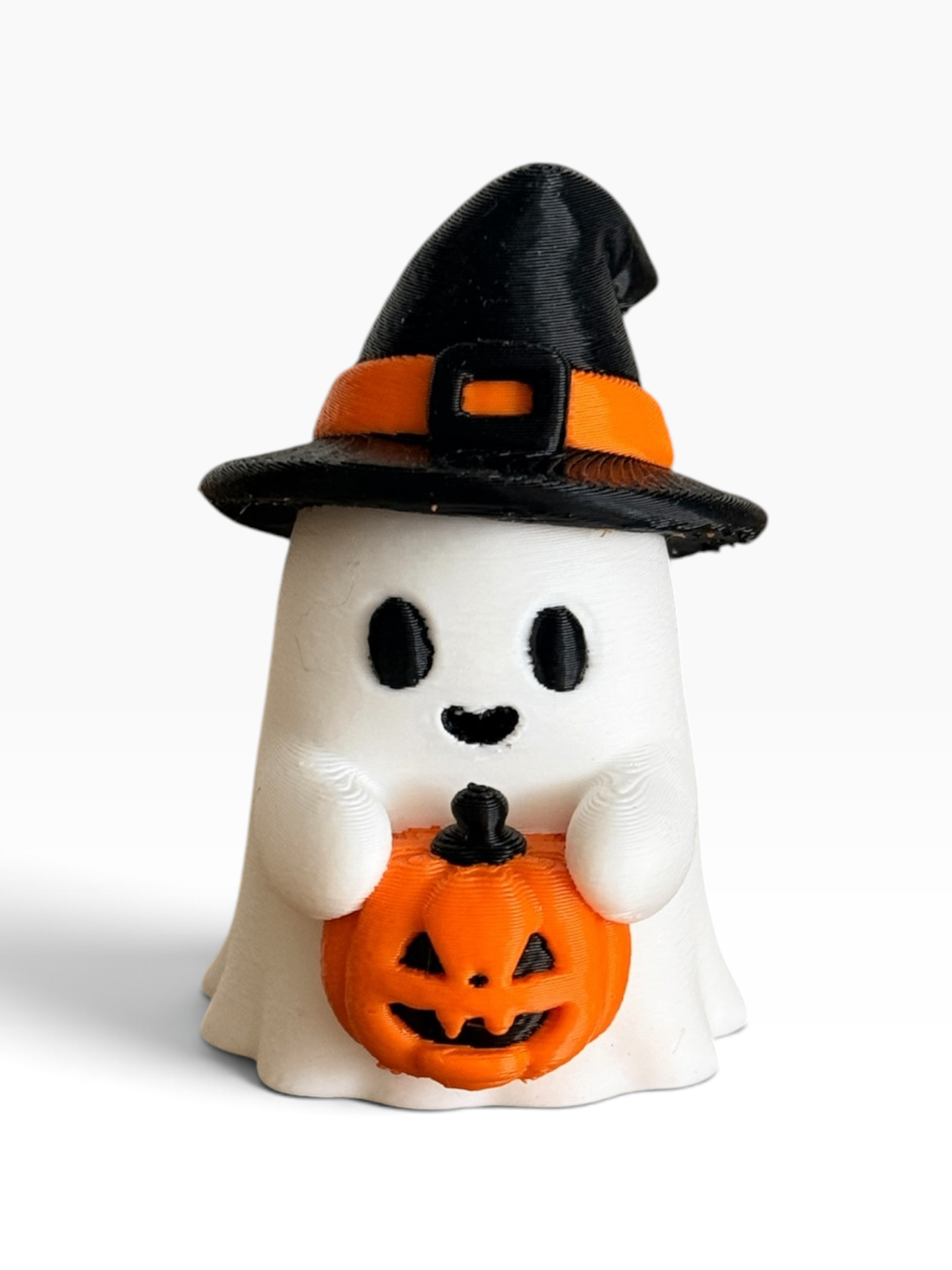 A cute 3d printed white ghost Halloween decoration wearing a black witch hat with an orange band and holding a carved orange pumpkin, set against a plain white background.