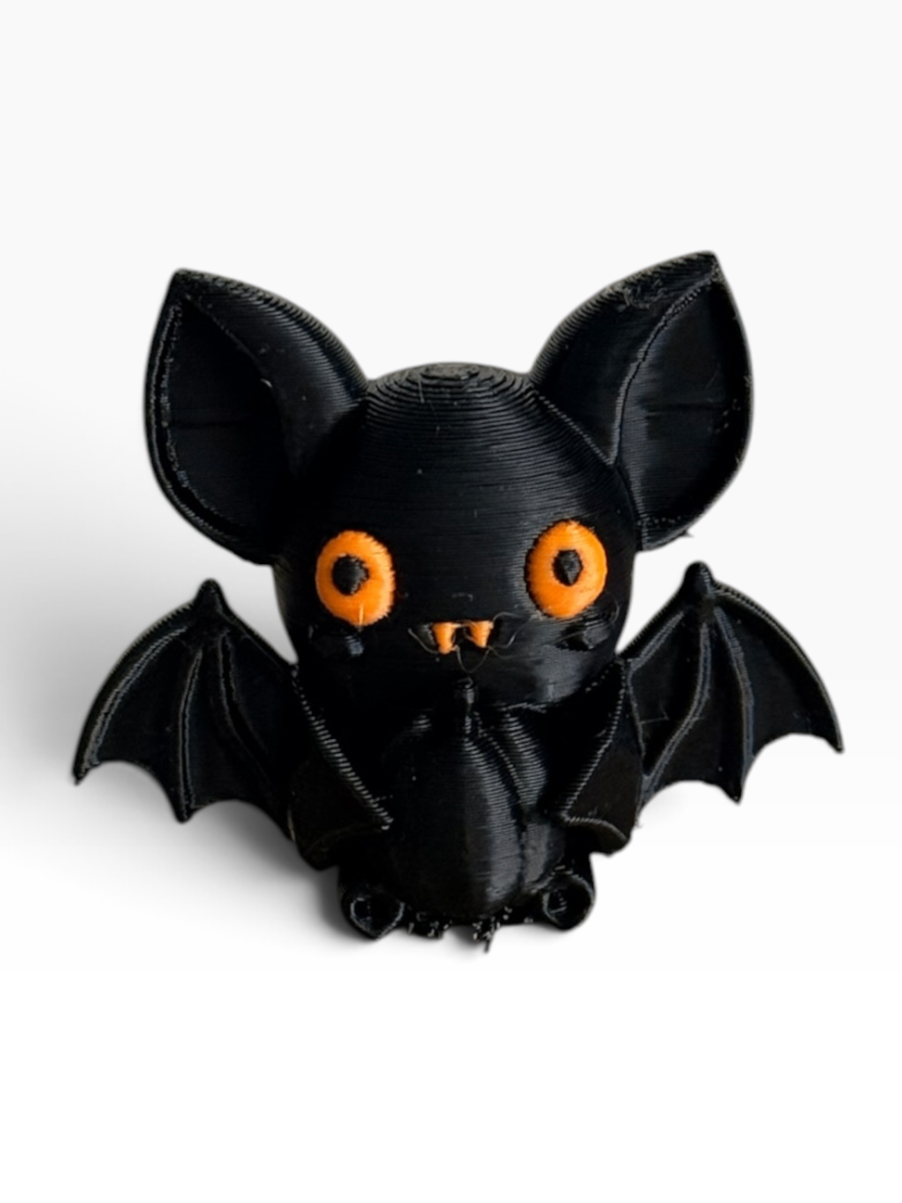 A black 3D-printed cute bat figurine with bright orange eyes and small orange details, shown against a plain white background.