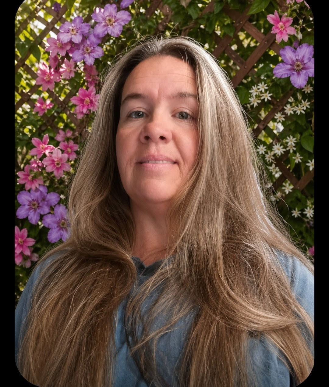 Woman with long blonde hair standing in front of a floral background