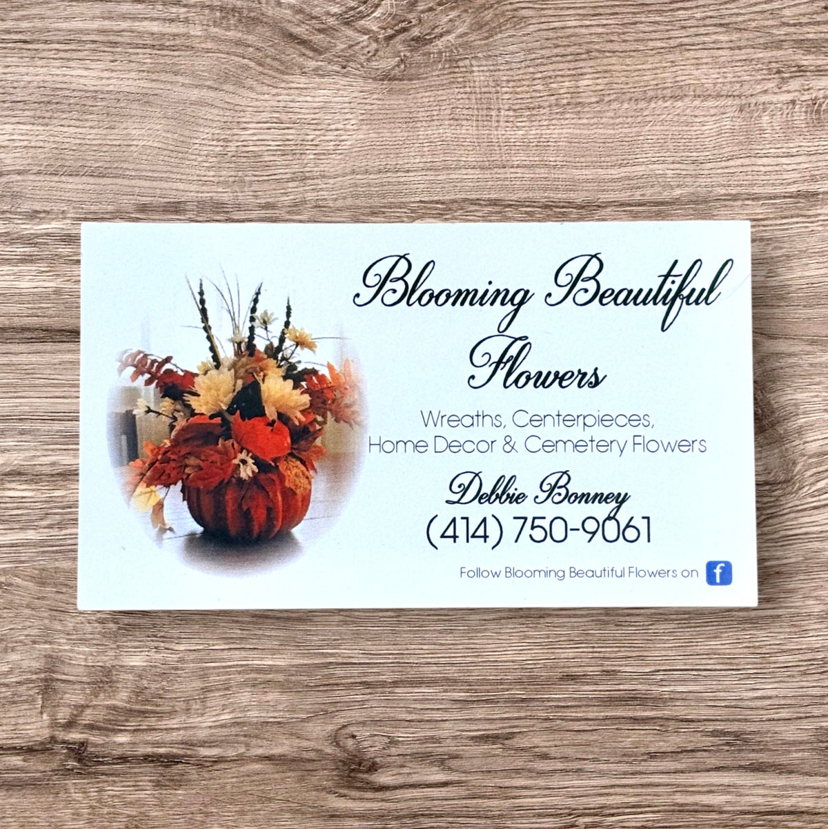 Business card for Blooming Beautiful Flowers with a floral arrangement on a wooden surface