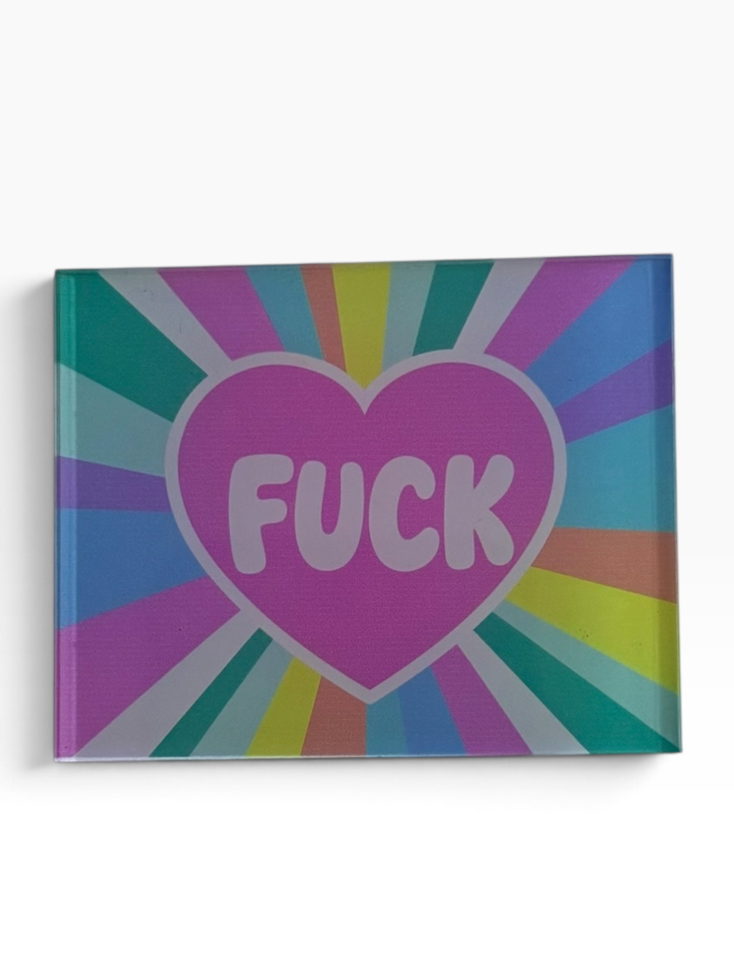 A rectangular acrylic magnet featuring a pink heart with the word 'FUCK' in white, set against a colorful retro sunburst background of purple, blue, green, yellow, and orange rays.