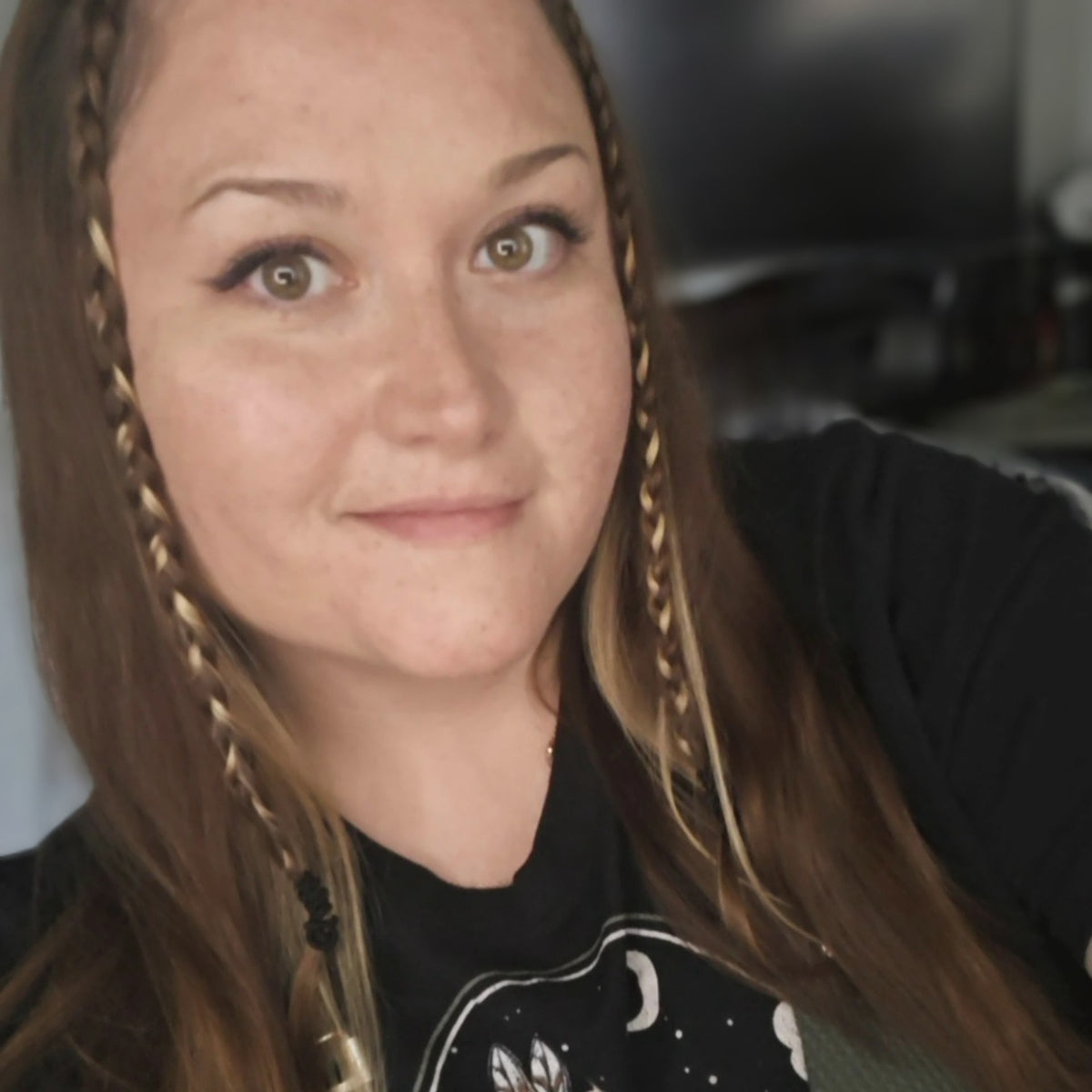 Woman with braided hair wearing a black shirt with a graphic design.