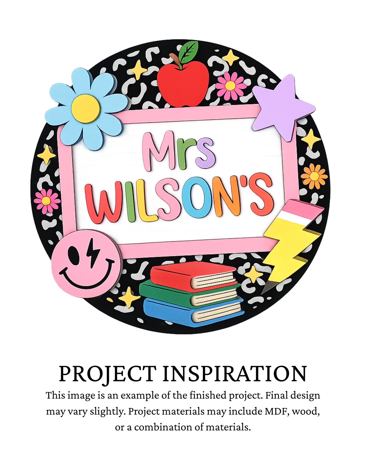 A colorful decorative sign design reading 'Mrs. Wilson's' with an apple, flowers, stars, smiley face, books, and a lightning bolt on a black patterned circular background, plus text below saying 'PROJECT INSPIRATION' describing it as a finished project example.
