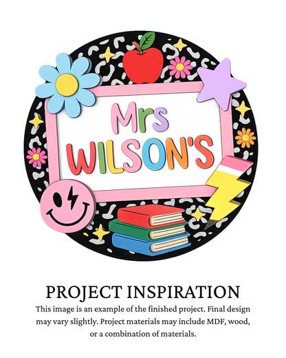 A colorful decorative sign design reading 'Mrs. Wilson's' with an apple, flowers, stars, smiley face, books, and a lightning bolt on a black patterned circular background, plus text below saying 'PROJECT INSPIRATION' describing it as a finished project example.