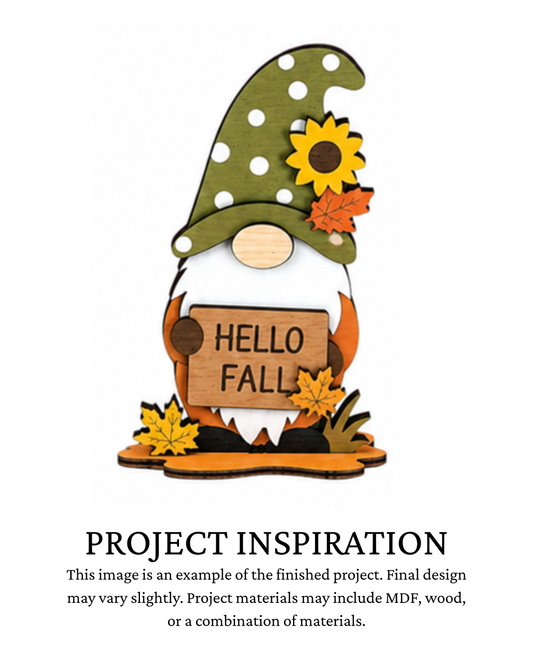 Finished project example of a layered fall gnome shelf sitter wearing a green hat with sunflower accents and holding a “Hello Fall” sign. Text below reads “PROJECT INSPIRATION,” describing it as a finished project example.