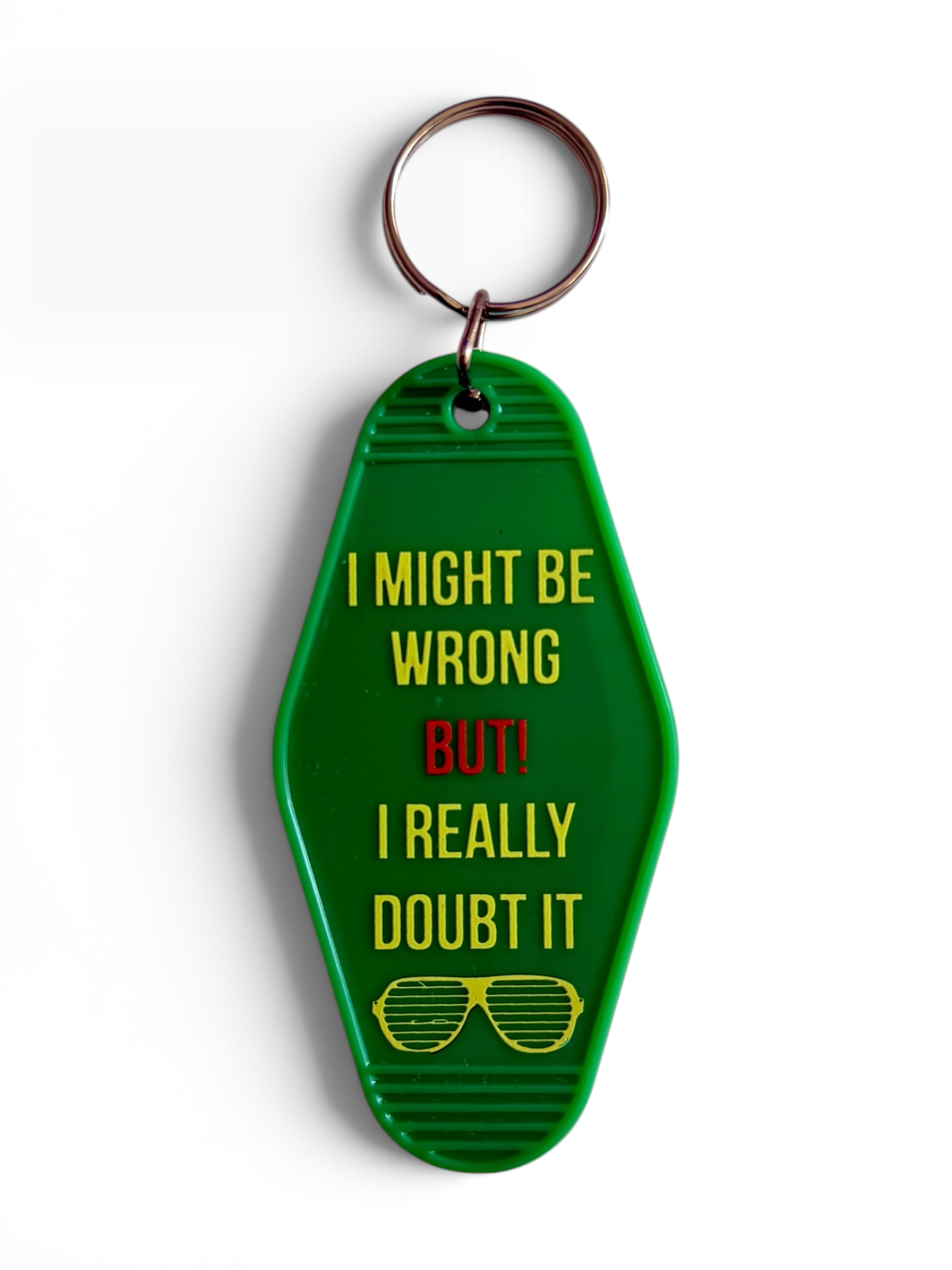 A green plastic retro keychain shaped like a motel key card with the text 'I MIGHT BE WRONG BUT! I REALLY DOUBT IT' in yellow and red, plus a yellow sunglasses graphic, attached to a metal key ring on a white background.
