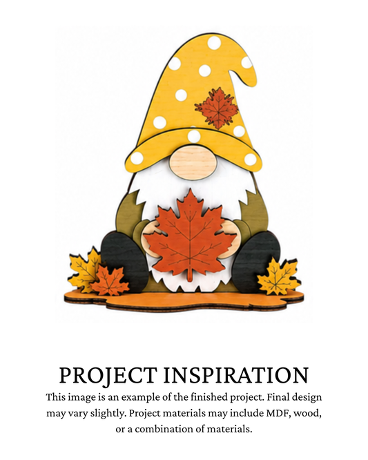 Finished project example of a layered fall gnome shelf sitter wearing a yellow hat and holding a large red-orange maple leaf with fall leaves at the base. Text below reads “PROJECT INSPIRATION,” describing it as a finished project example.
