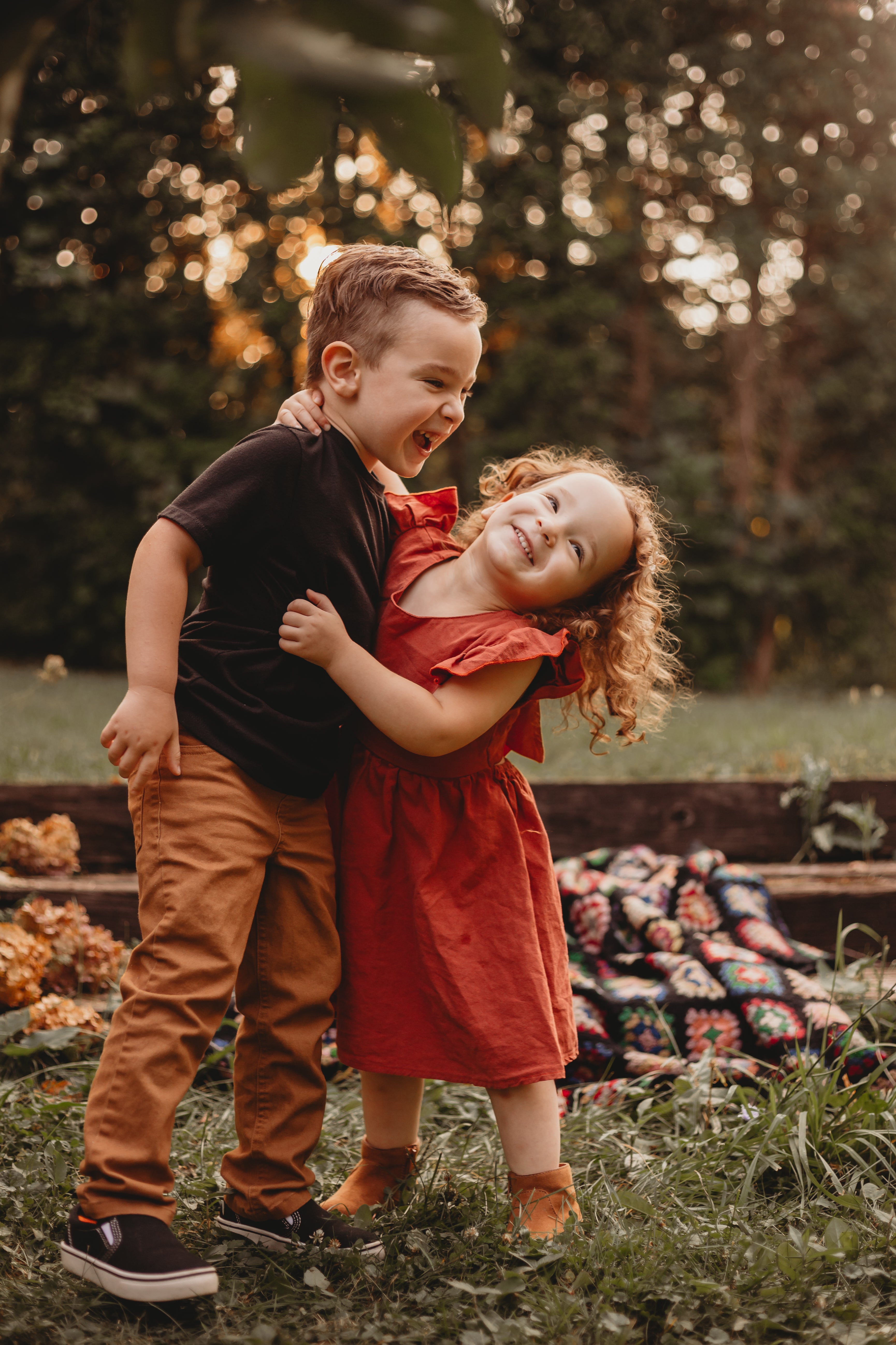 Photo of two children hugging each other. Standing in a wood area, smiling laughing.