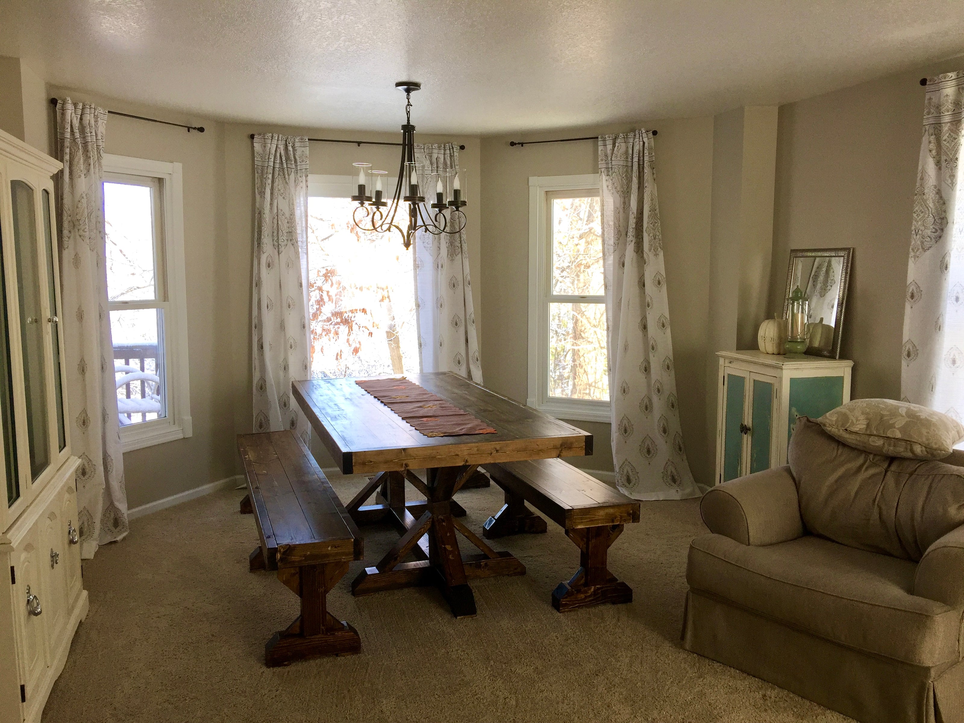 A photo of a dining room with a rustic chic decor. featuring a large dark wooden table and benches. 