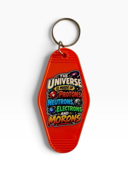 A bright orange keychain shaped like a retro motel key card, featuring a metal split ring and a colorful printed graphic that reads 'The Universe Is Made Of Protons Neutrons Electrons And Morons' on a clean white background.