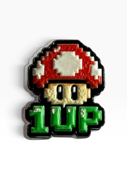 A pixel-art acrylic uv printed pin of a classic video game mushroom with the text '1 UP' below it, on a clean white background.