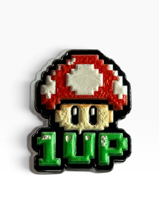 A pixel-art acrylic uv printed pin of a classic video game mushroom with the text '1 UP' below it, on a clean white background.