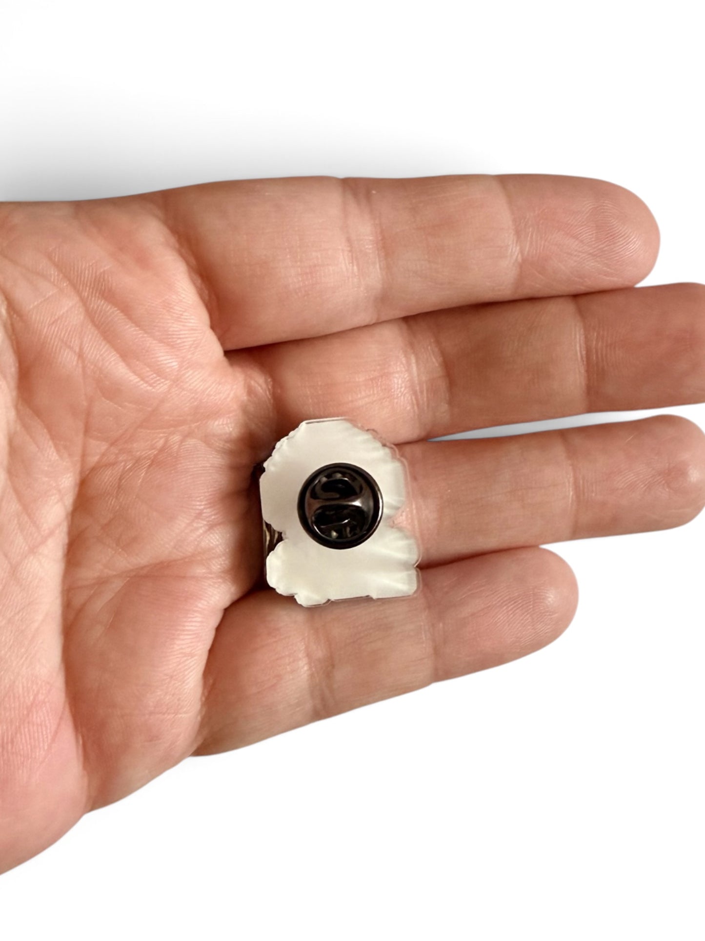 A small lapel pin back resting on an open hand against a plain white background.