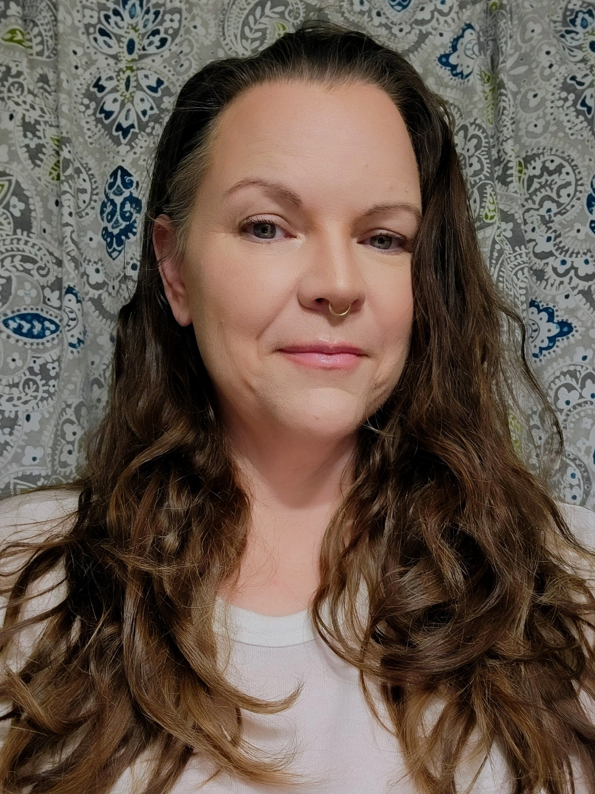 Woman with long brown hair against a patterned wall