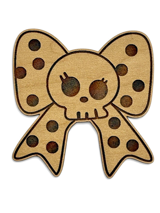 Engraved wooden Halloween magnet featuring a skull with oversized polka dot bow