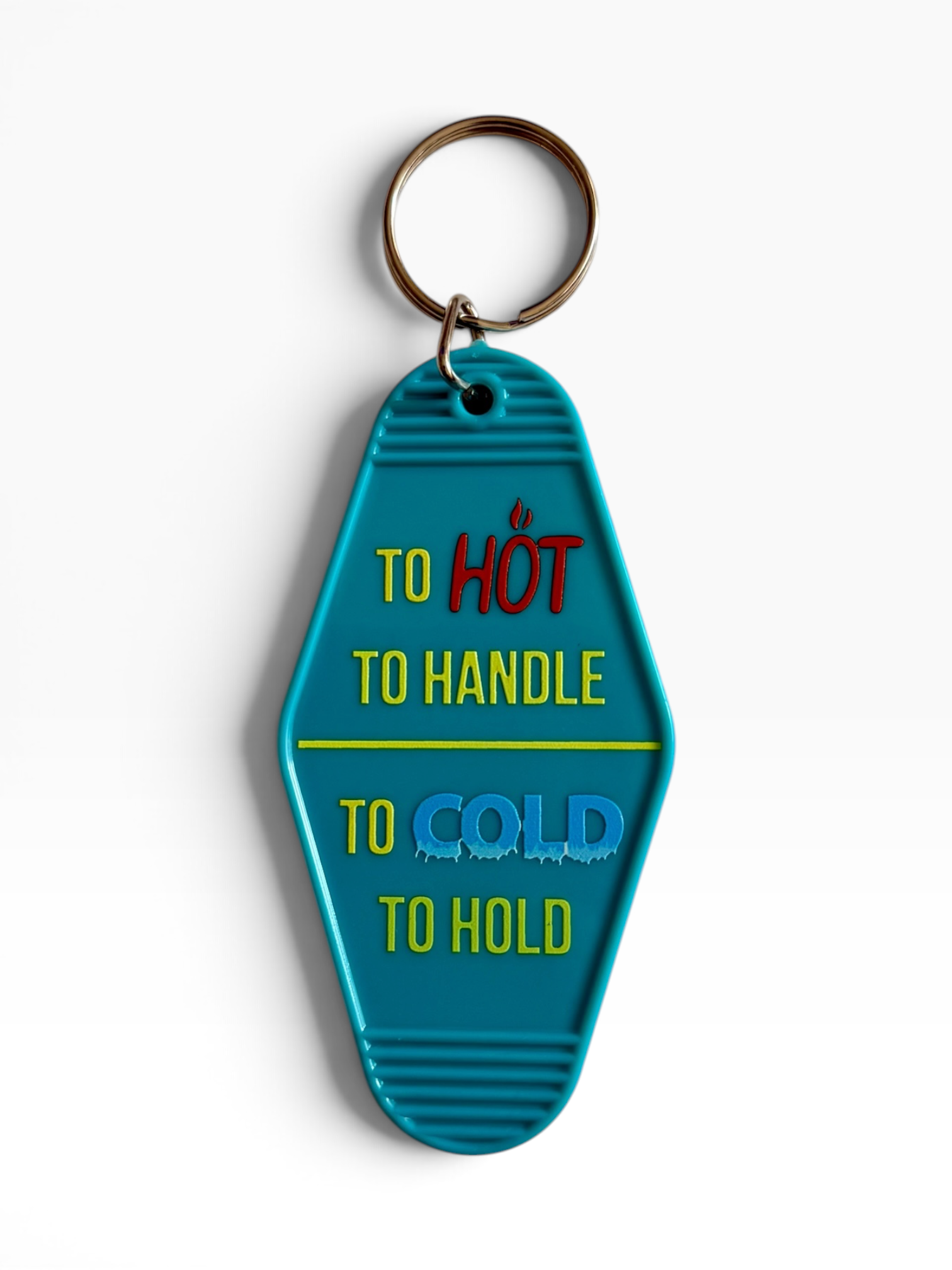 A turquoise blue retro hotel keychain with a metal split ring. The keychain features humorous text : 'TO HOT', 'TO HANDLE', 'TO COLD', and 'TO HOLD' in yellow, red, and blue lettering, set against a clean white background.