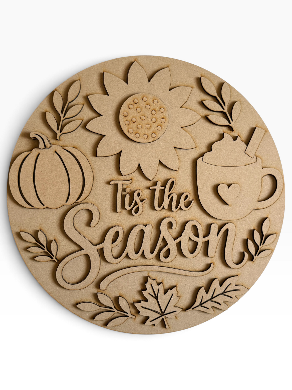 A round laser-cut mdf round sign featuring autumn-themed designs including a pumpkin, sunflower, leaves, a hot cocoa mug with a heart, and the phrase 'Tis the Season' in elegant script, shown on a clean white background.