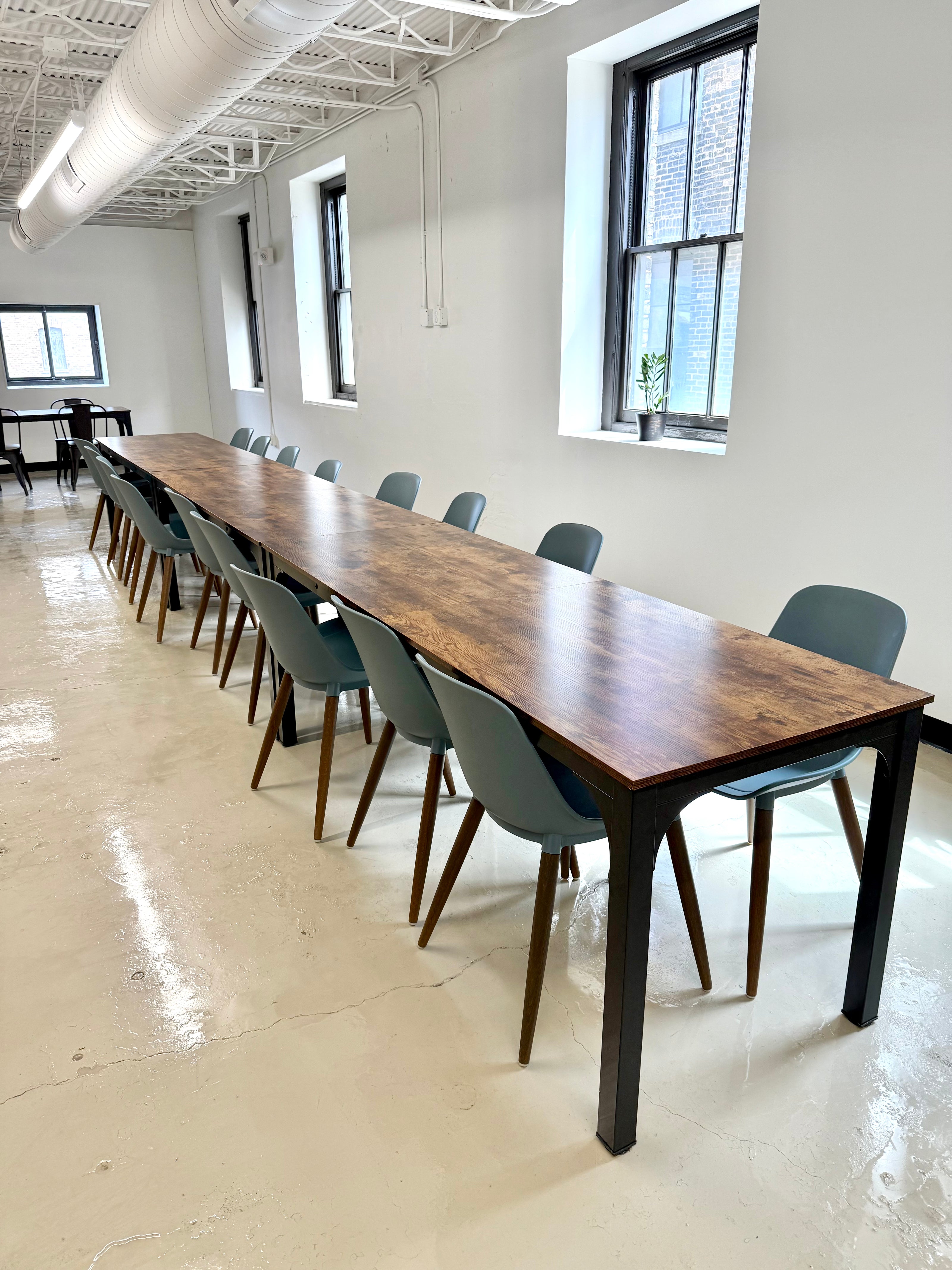 Long wooden conference table with chairs in an industrialized work space setting
